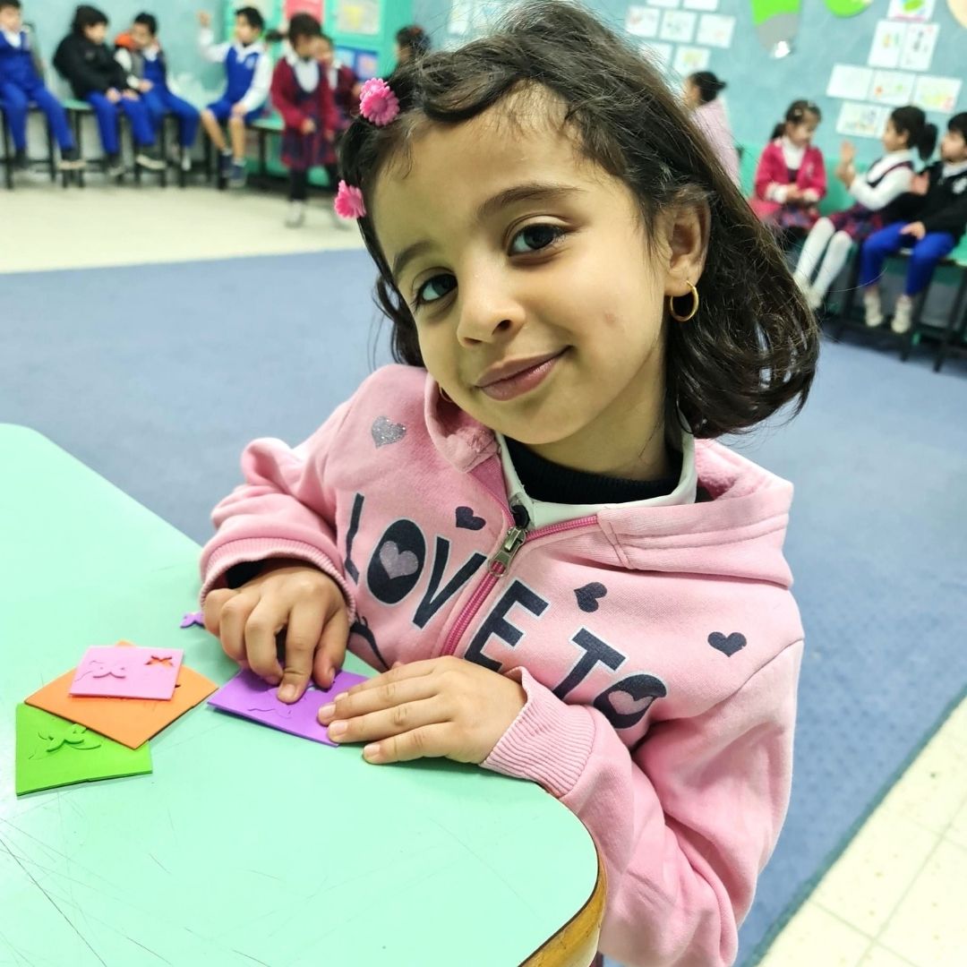Nabila at school table, pink hoodie